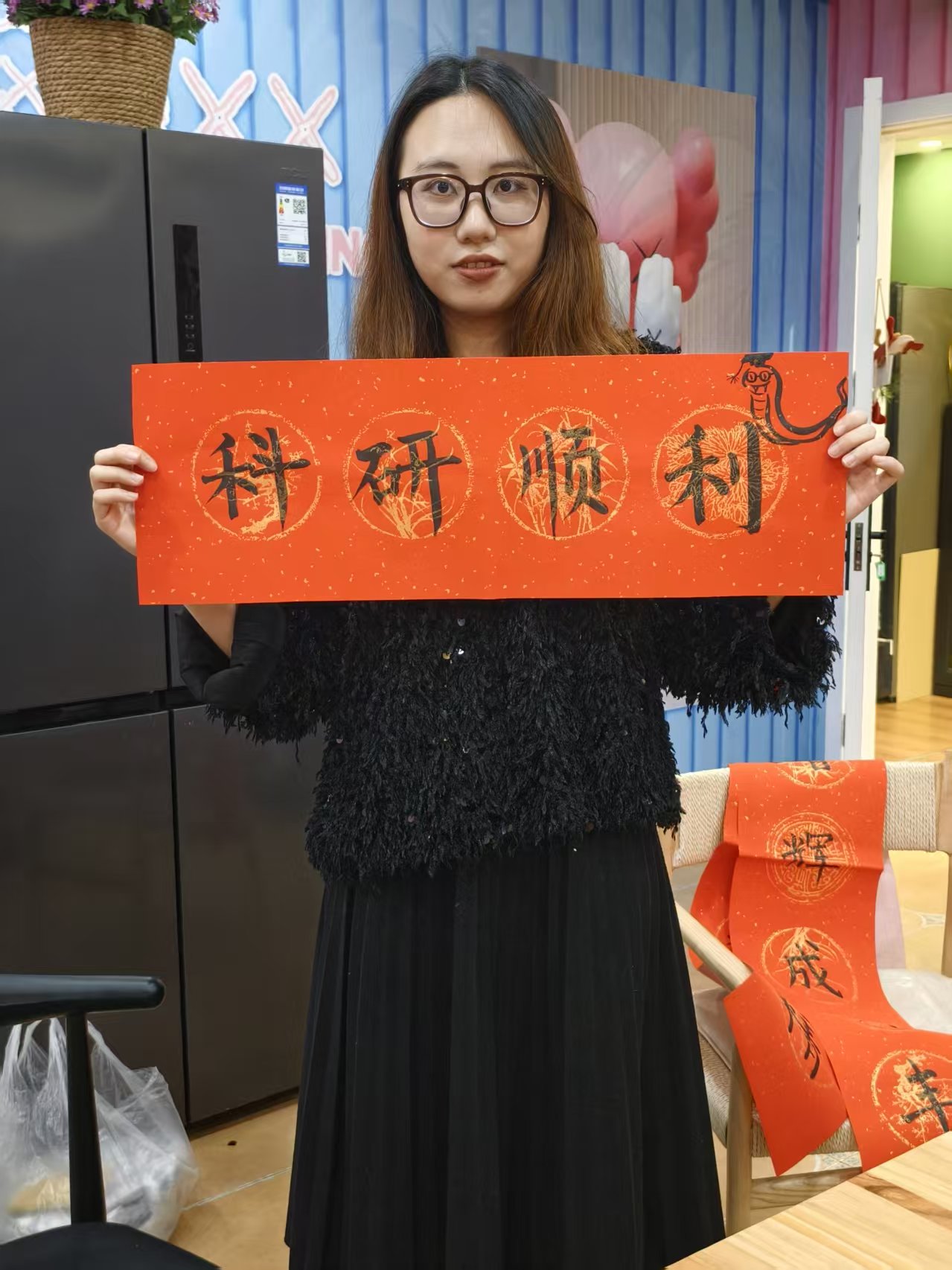 曹馨尹拿着科研顺利字幅